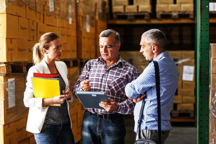 Team of customs managers and warehouse worker checking list and inventory