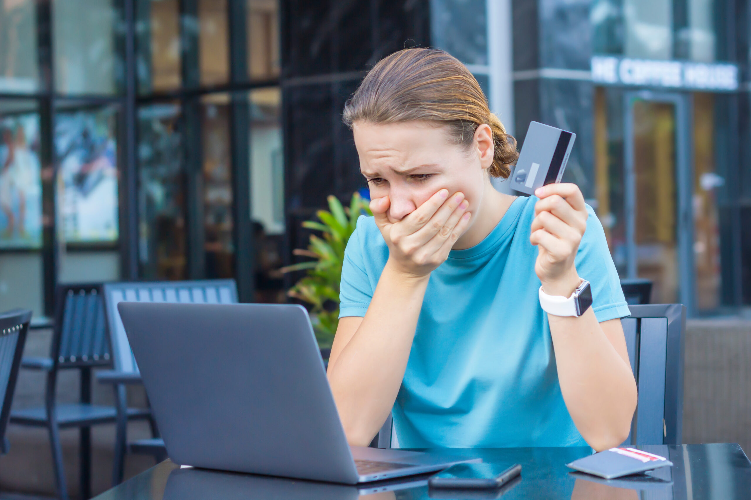 nervous and horrified woman holding credit card and using her laptop