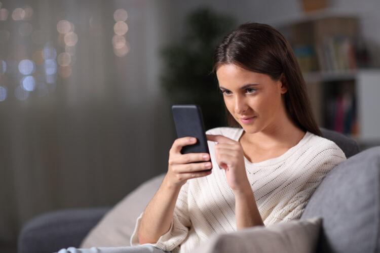 Girl checking mobile phone sitting at home