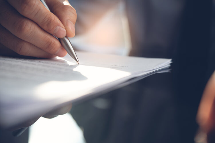 Male hand signing a document.