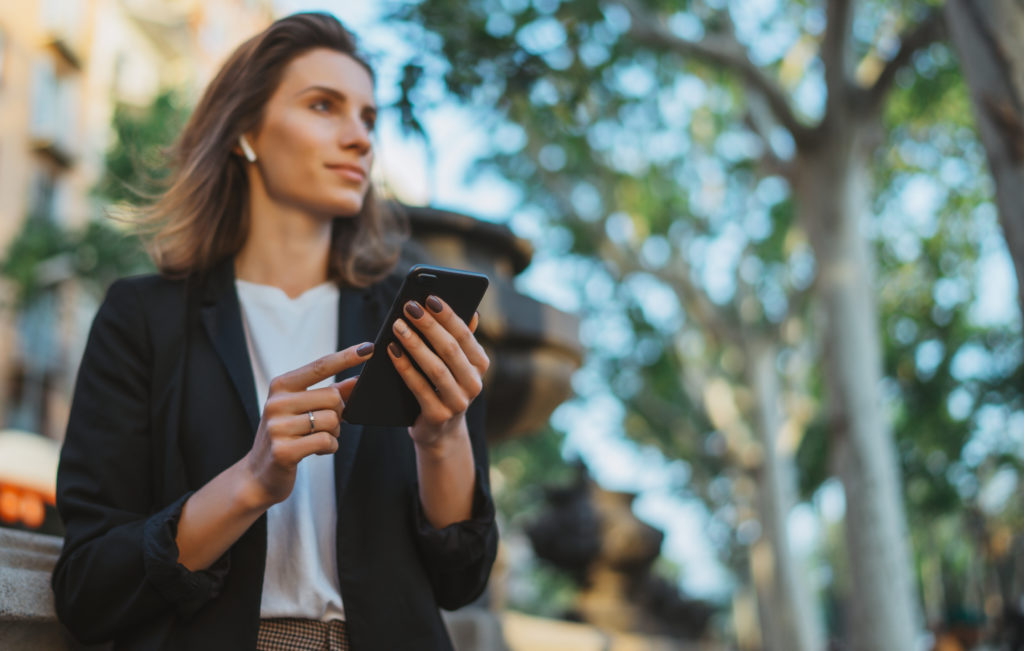 young  businesswoman writes messages on smartphone while walking