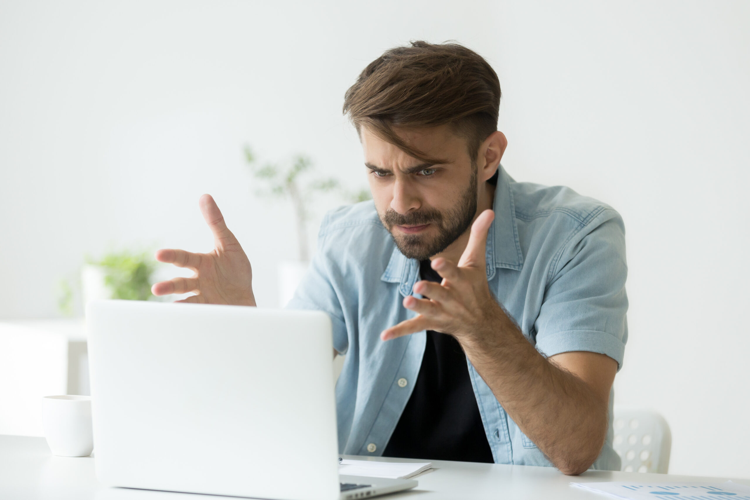 Angry man disagree with fake online news looking at laptop