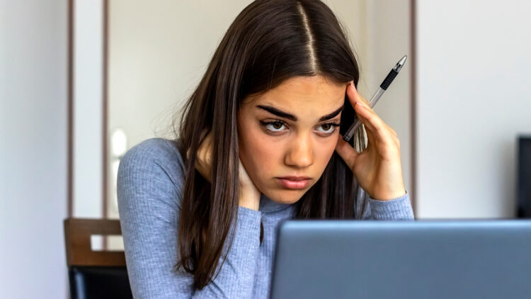 Serious young woman with a worried expression sitting in front of laptop