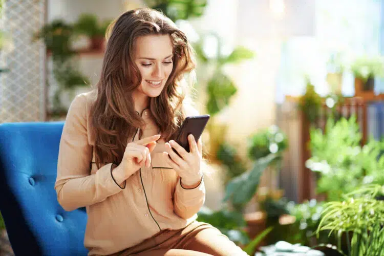 smiling woman in sunny day using phone applications