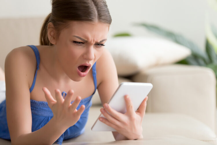 Annoyed young woman using digital tablet at home