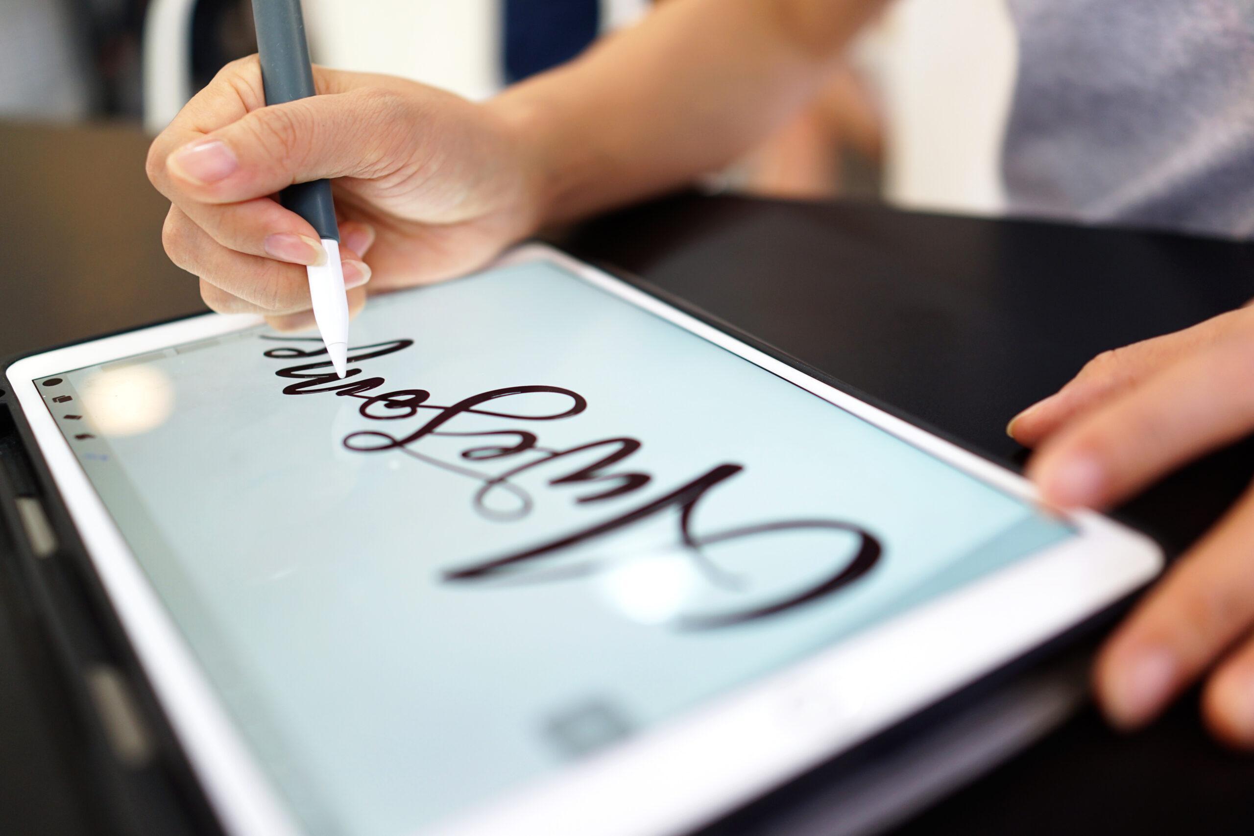 A female using Apple Pencil drawing hand lettering on a iPad usi