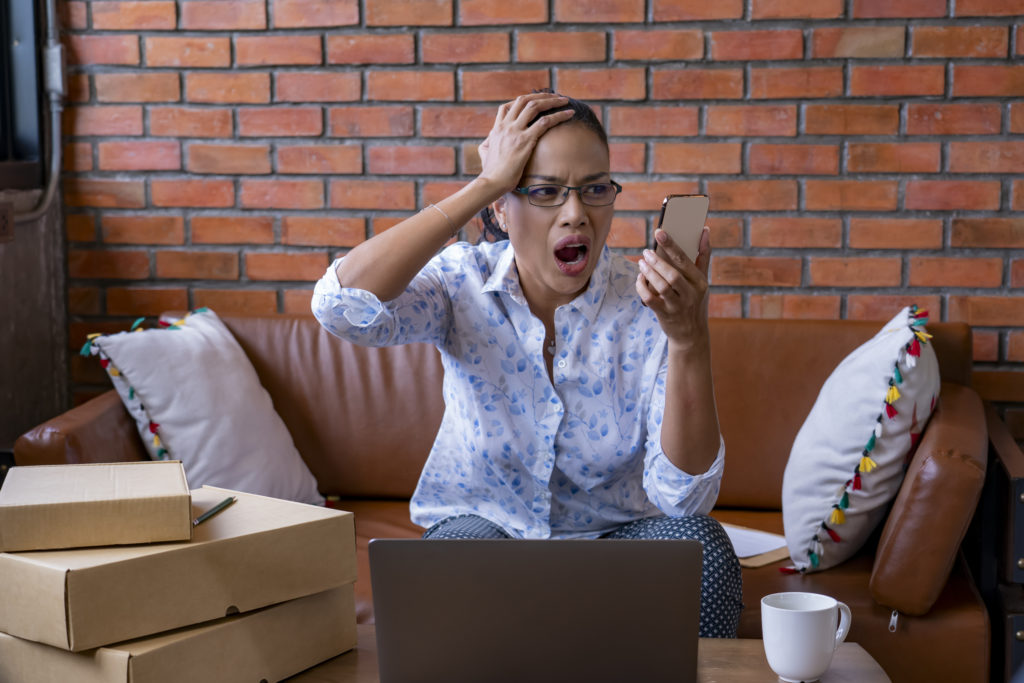 Unhappy woman having a customer cancel their order, reading on her phone.