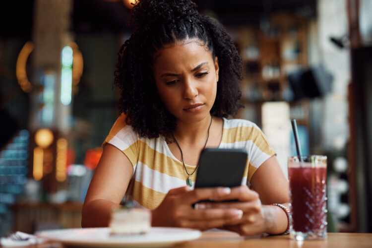 Distraught woman using phone at a coffee shop.