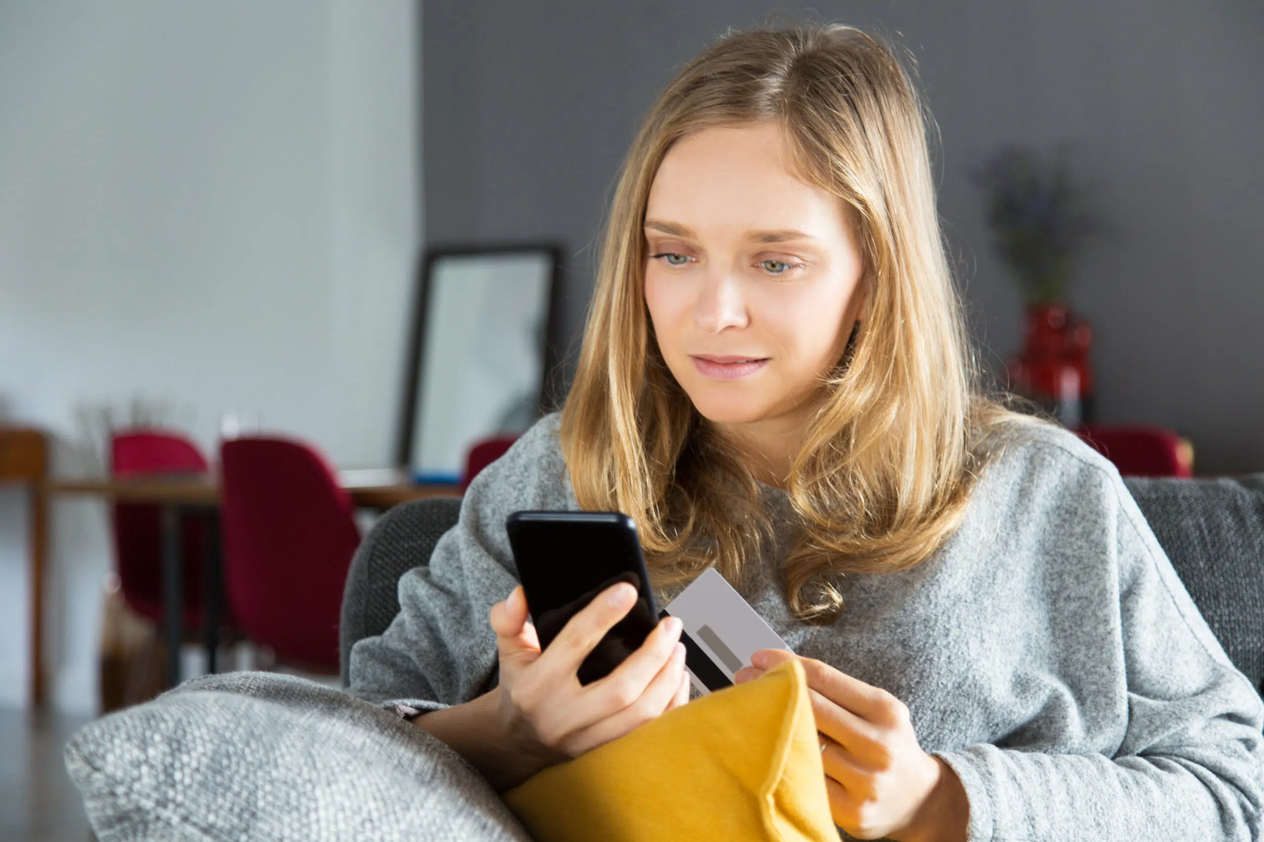 woman looks confused while purchasing online using her phone