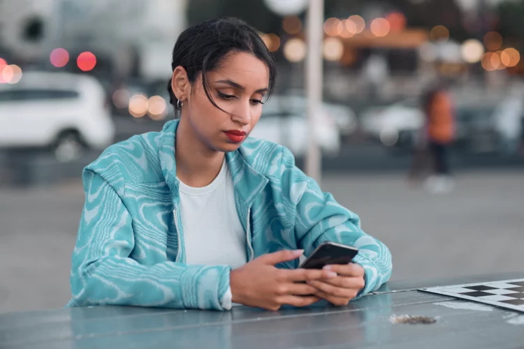 Sad looking woman using her mobile phone outdoor.