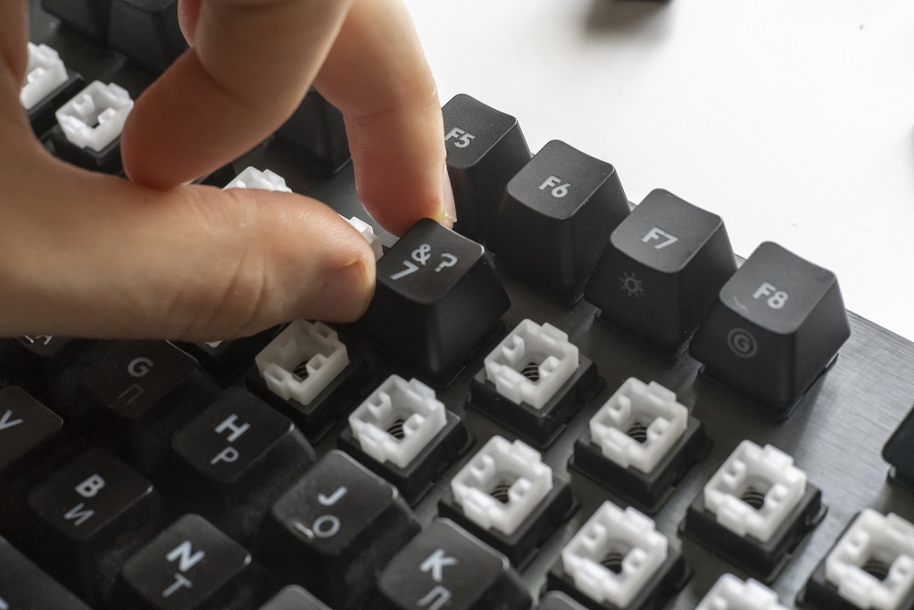 A gamer push the button on a mechanical keyboard with mechanical switches.