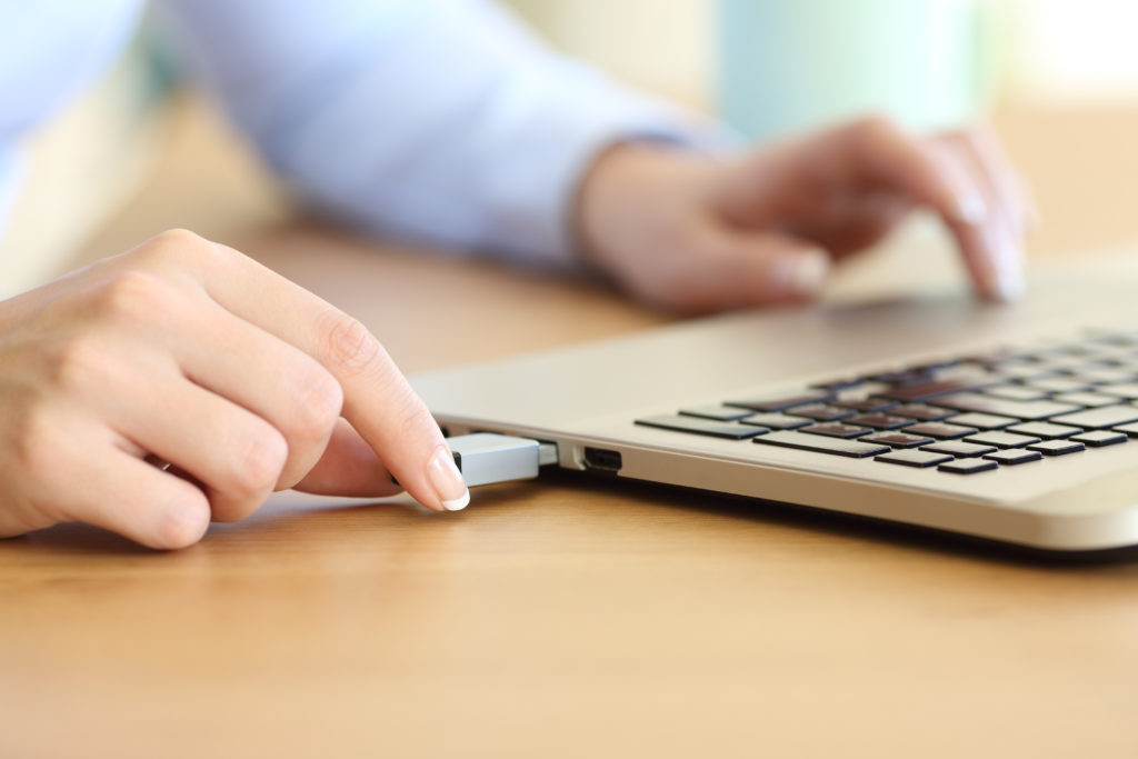 Close up of a woman hand connecting a pendrive in a laptop.