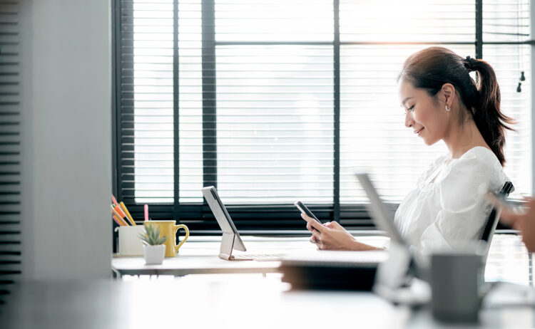 Young woman using smartphone while sitting at her office 