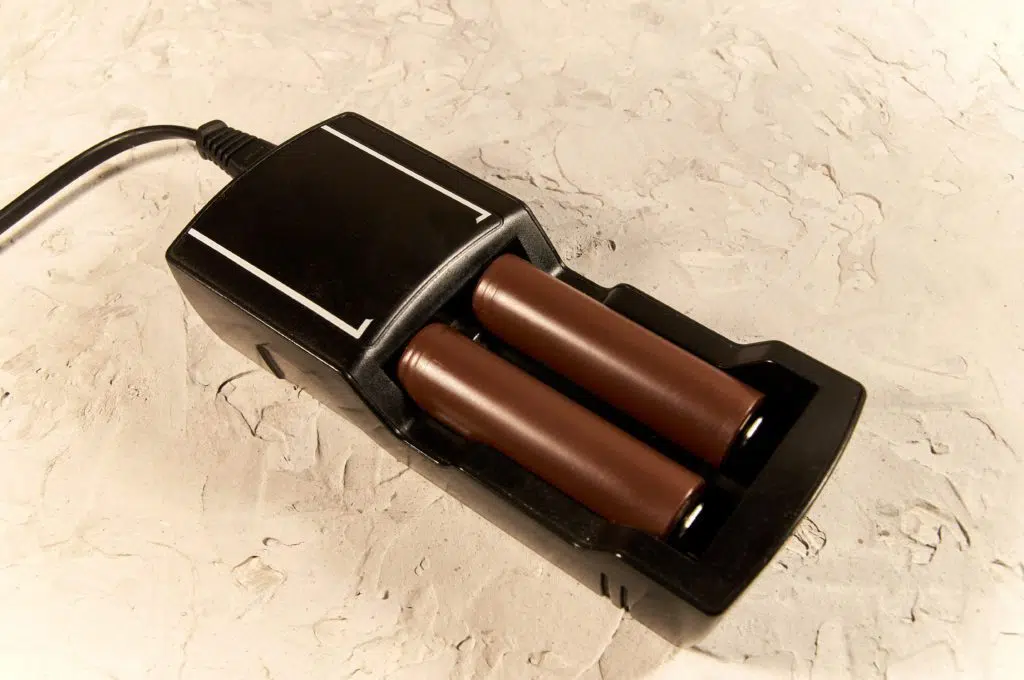 Black vape charger with two brown batteries.
