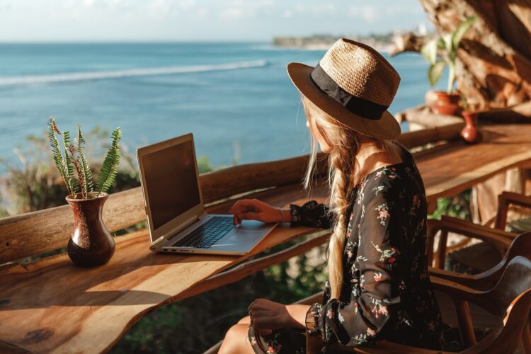 Freelancer woman working with computer on the beach.