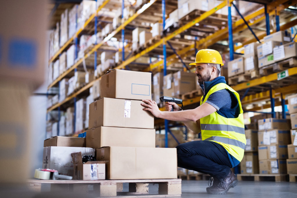 Warehouse worker with barcode scanner on the boxes.