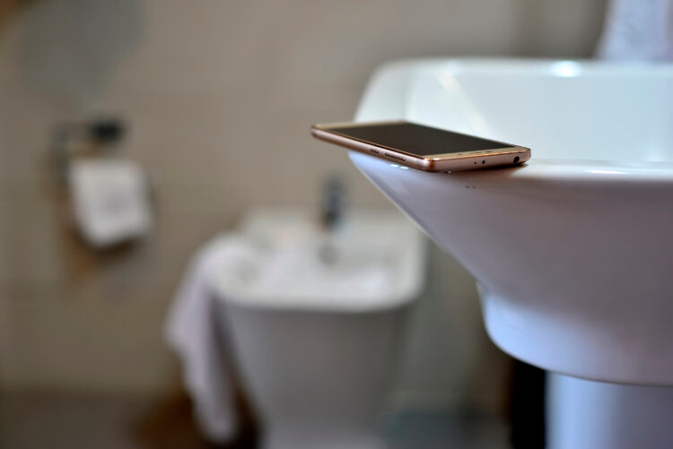 mobile phone on white washbasin and bidet