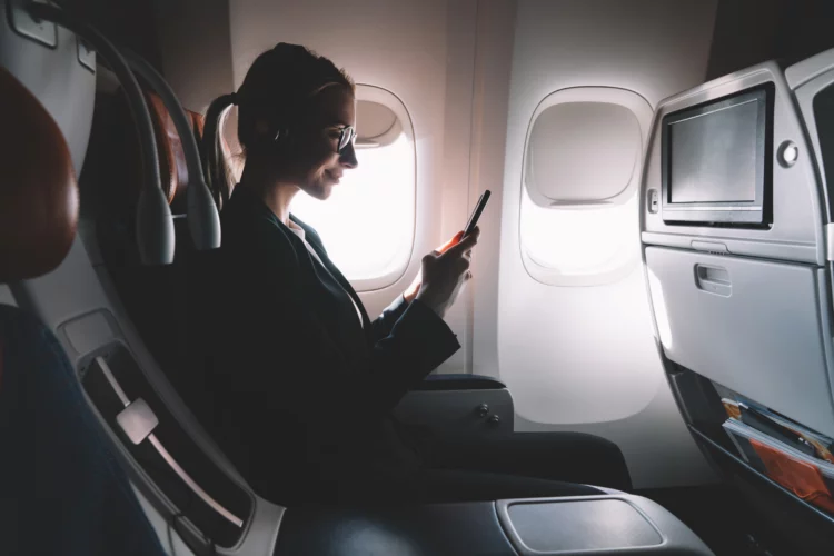 Silhouette of woman using phone onboard an aircraft.