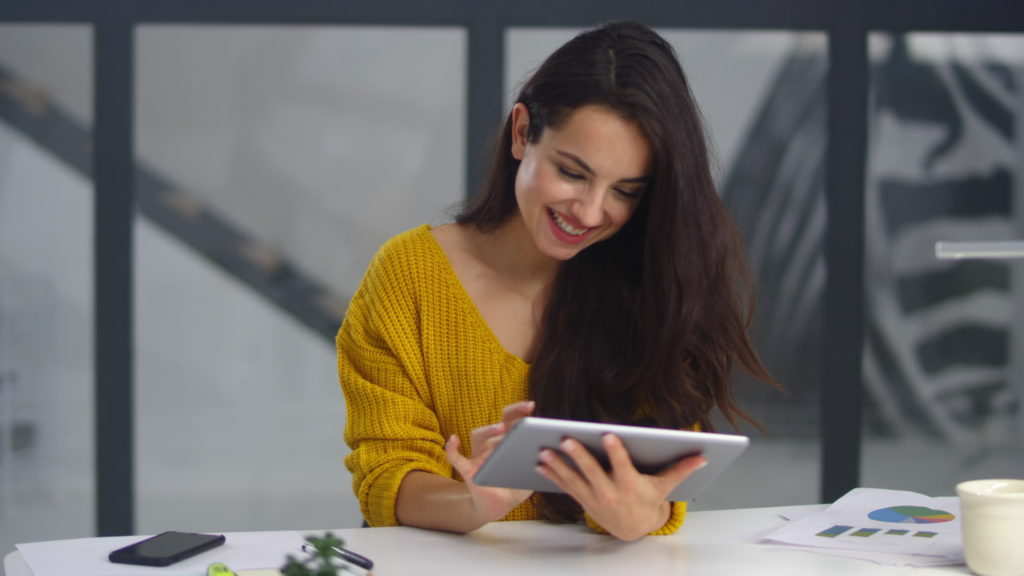 Smiling woman surfing internet on tablet device.