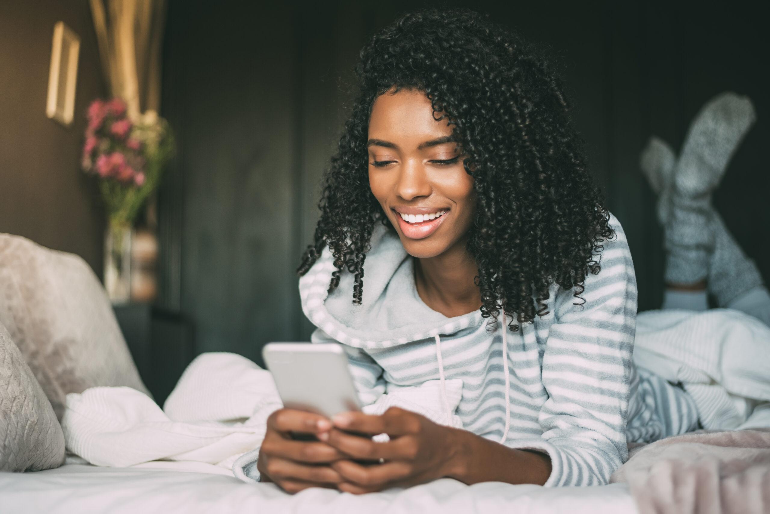 Pretty African-American woman using her smartphone in bed trying to make her Instagram account public