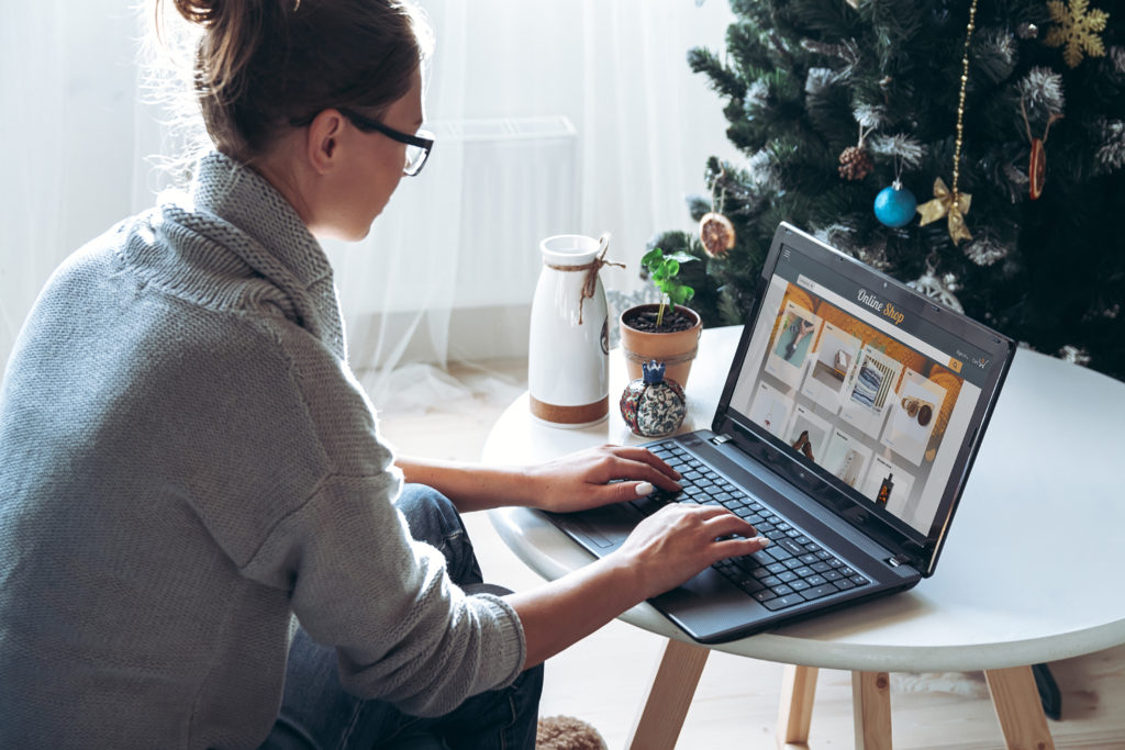 Young woman working on the laptop with christmas tree in the background.
