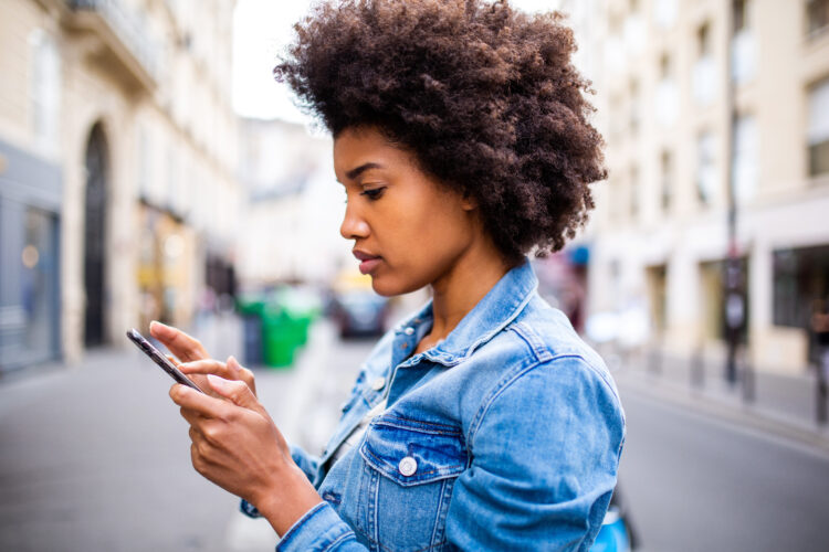Attractive yoing Afro woman with afro hair using her phone.