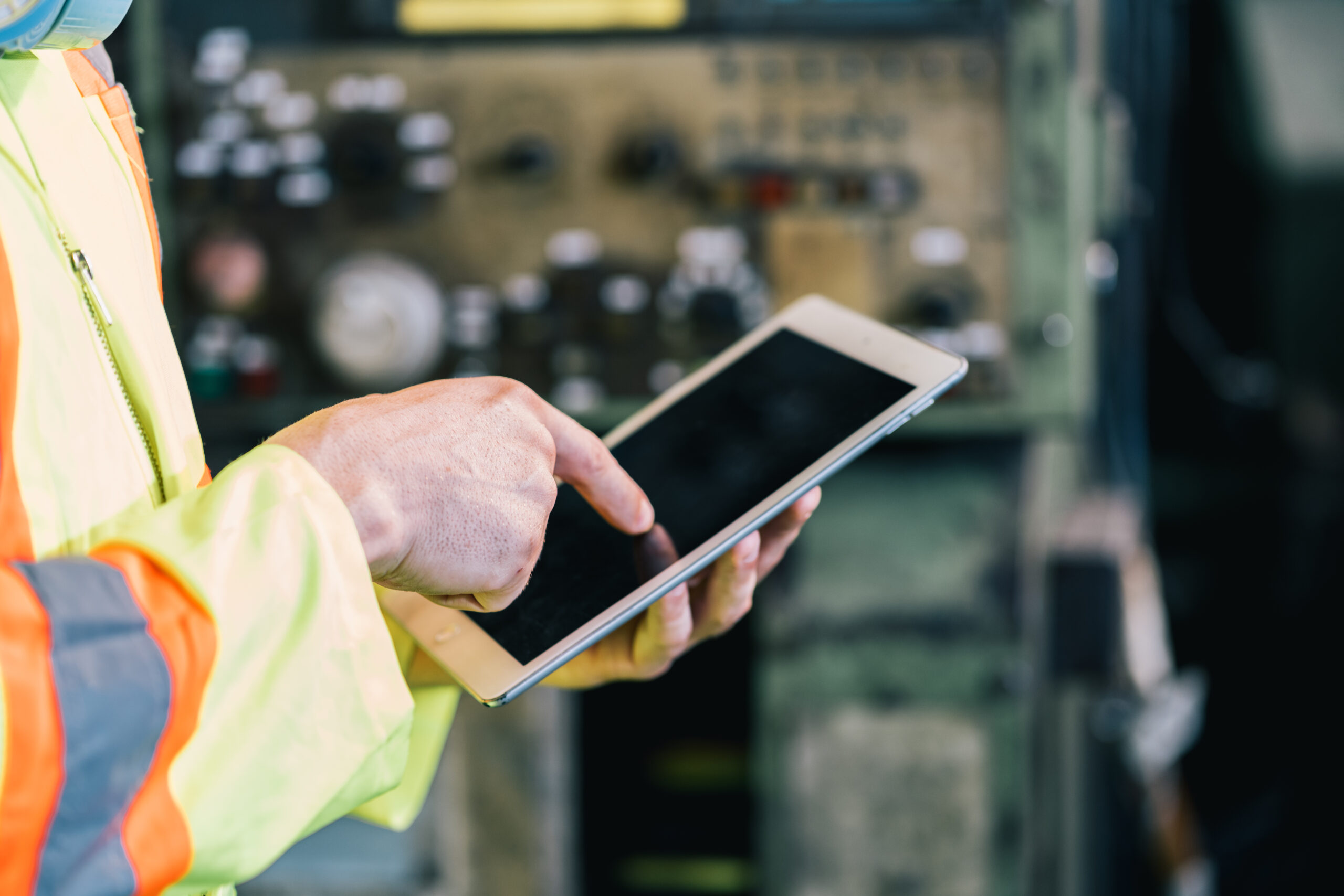 Worker in protective safety jumpsuit using a digital tablet on oil rig that does have WiFi but does not allow cell phones in most areas.