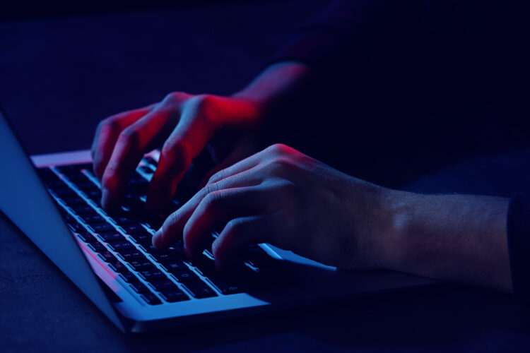 Professional hacker with laptop sitting at table