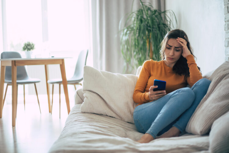 Frustrated and depressed young woman is crying with a smartphone in hand.