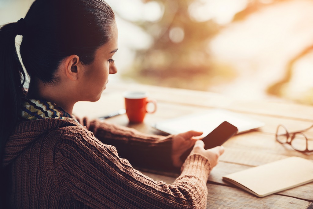 Young woman holding smart phone waiting for someone to call.