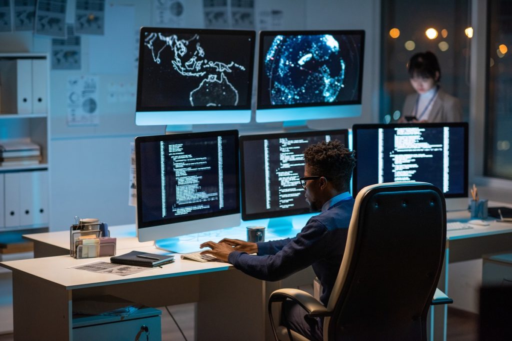 Man working in front of computer monitors.