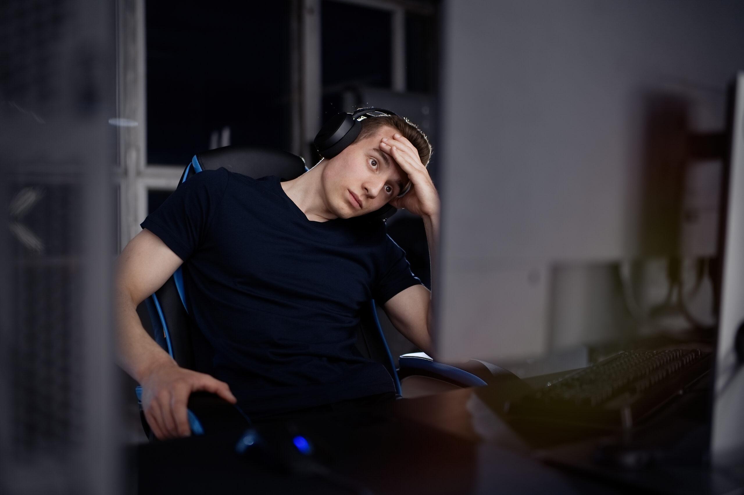 Young upset male gamer playing online video games on computer