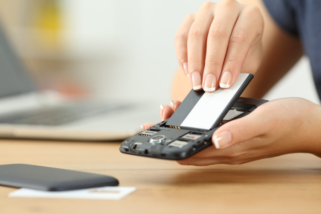 Woman's hand putting a battery into a smart phone.