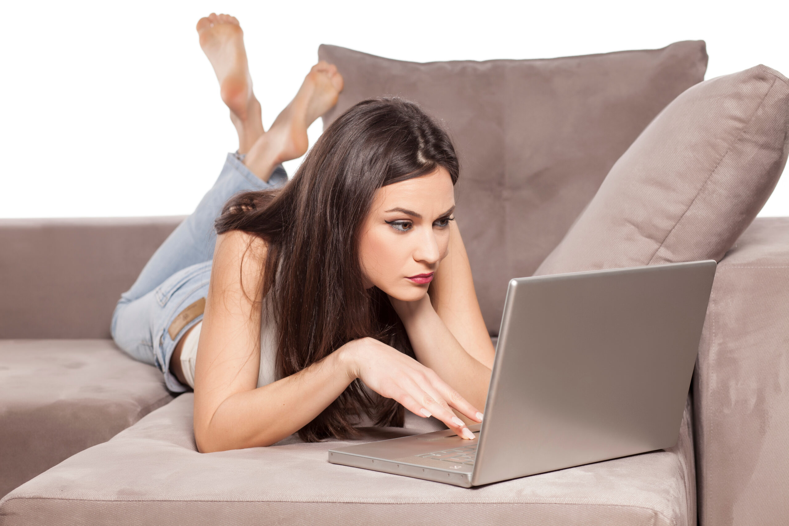 concerned girl lying on the couch and using her laptop