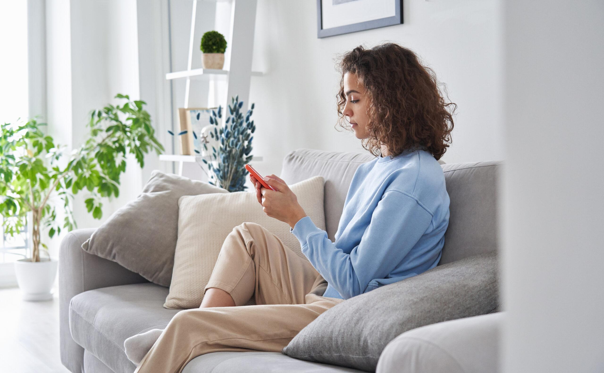 Woman using her smartphone while sitting on a sofa