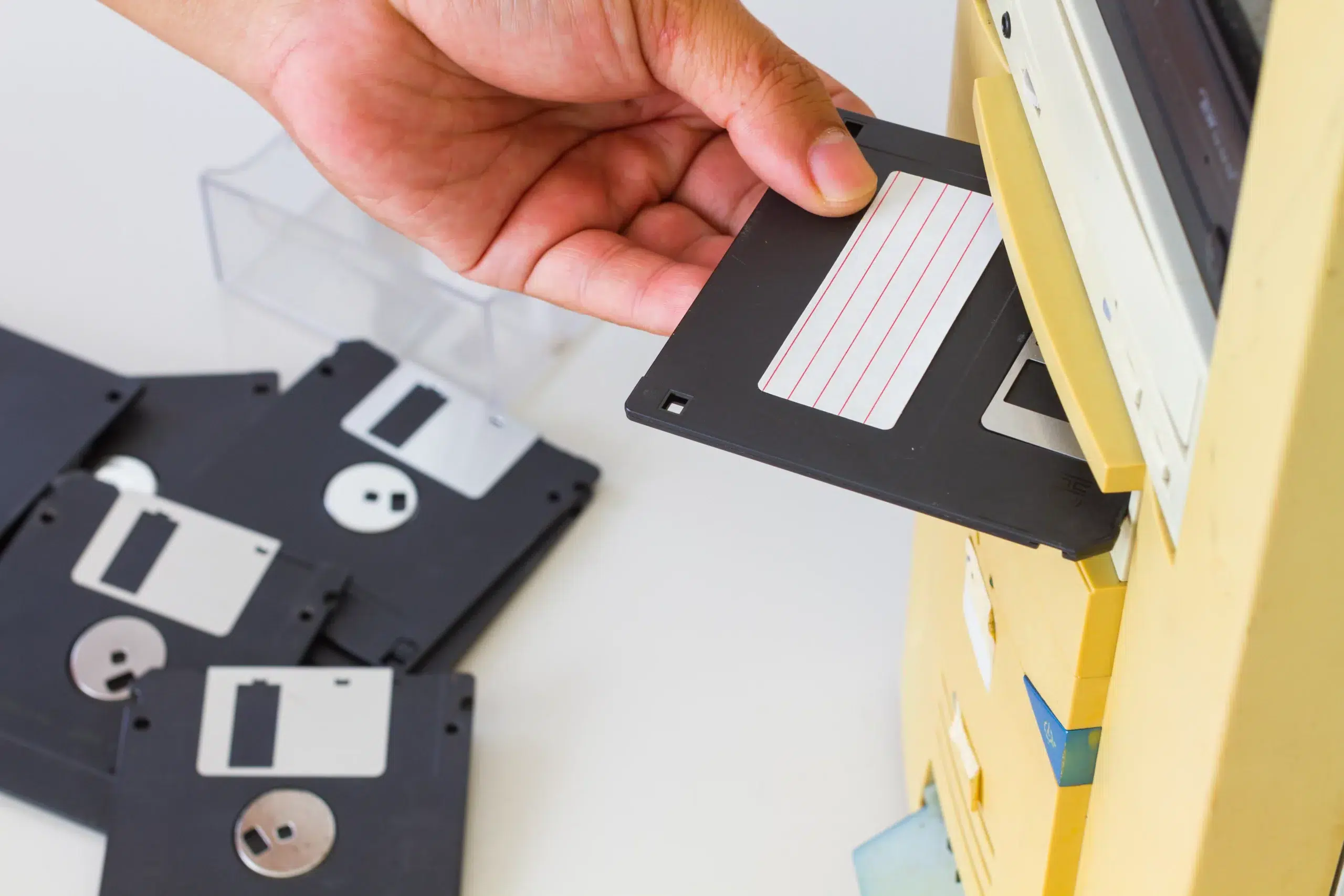 Hand inserting a 3.5-inch floppy disk into a floppy drive slot o