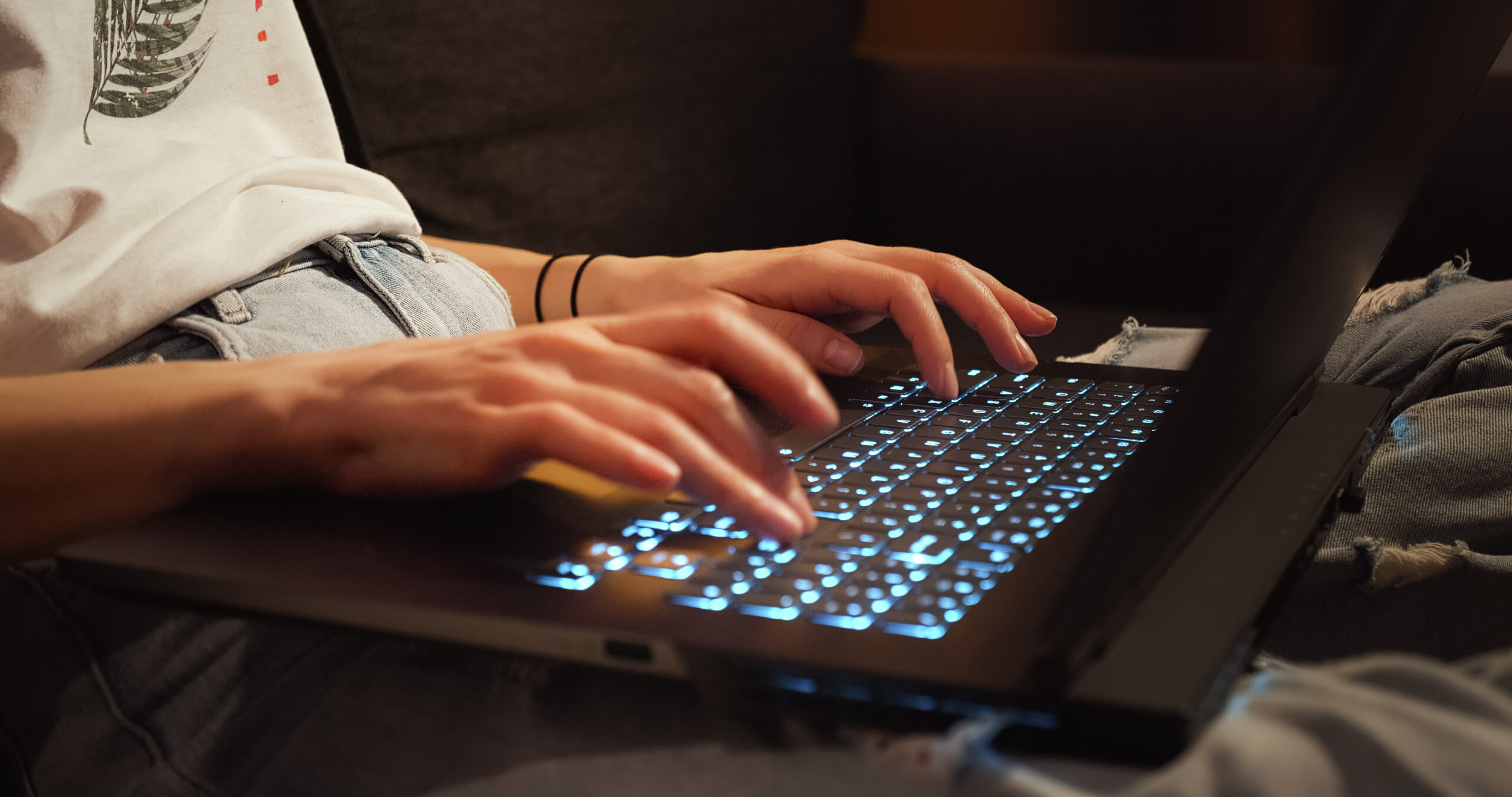 female hands typing on laptop keyboard with backlighting