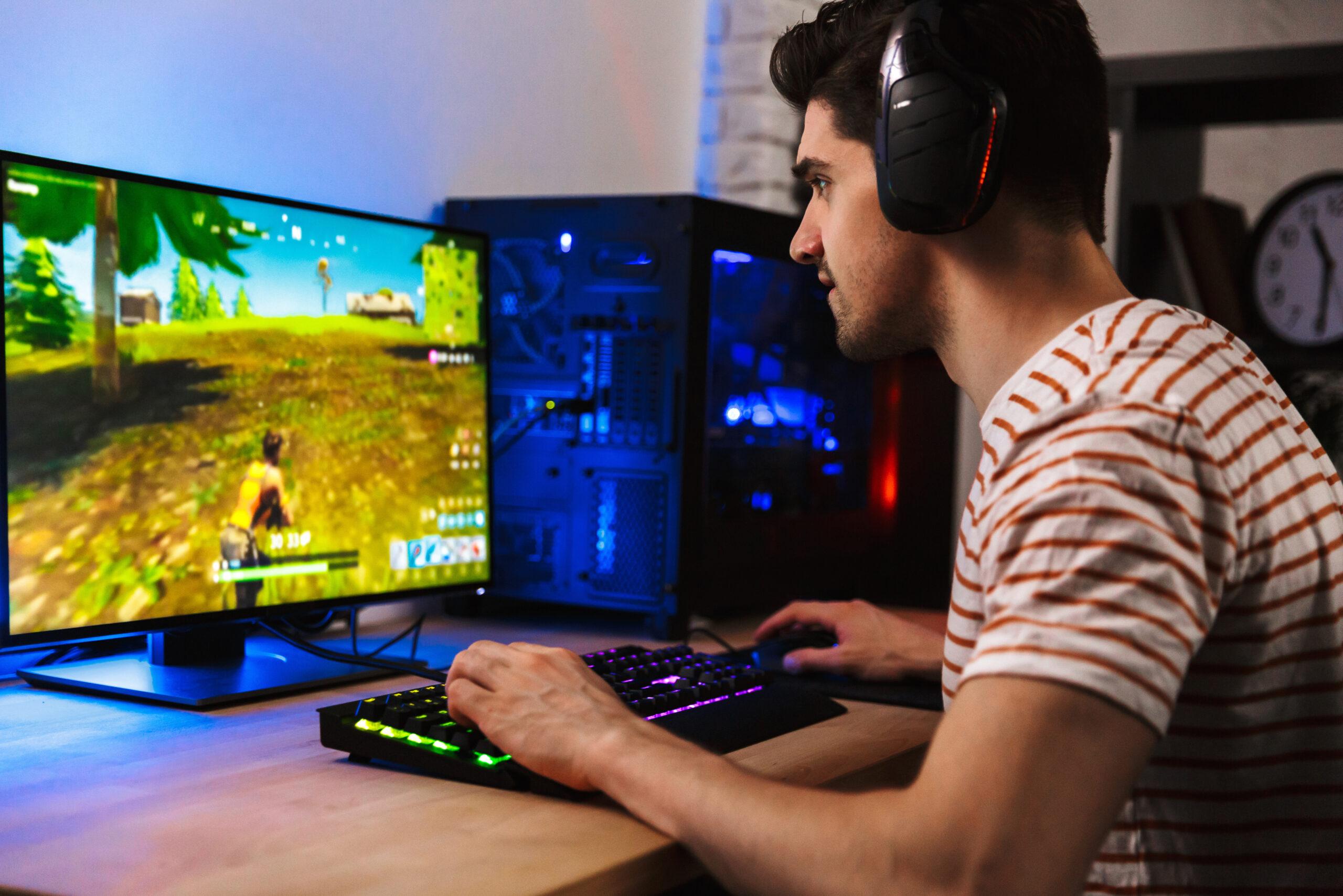 Image of young man playing video games on computer, wearing head