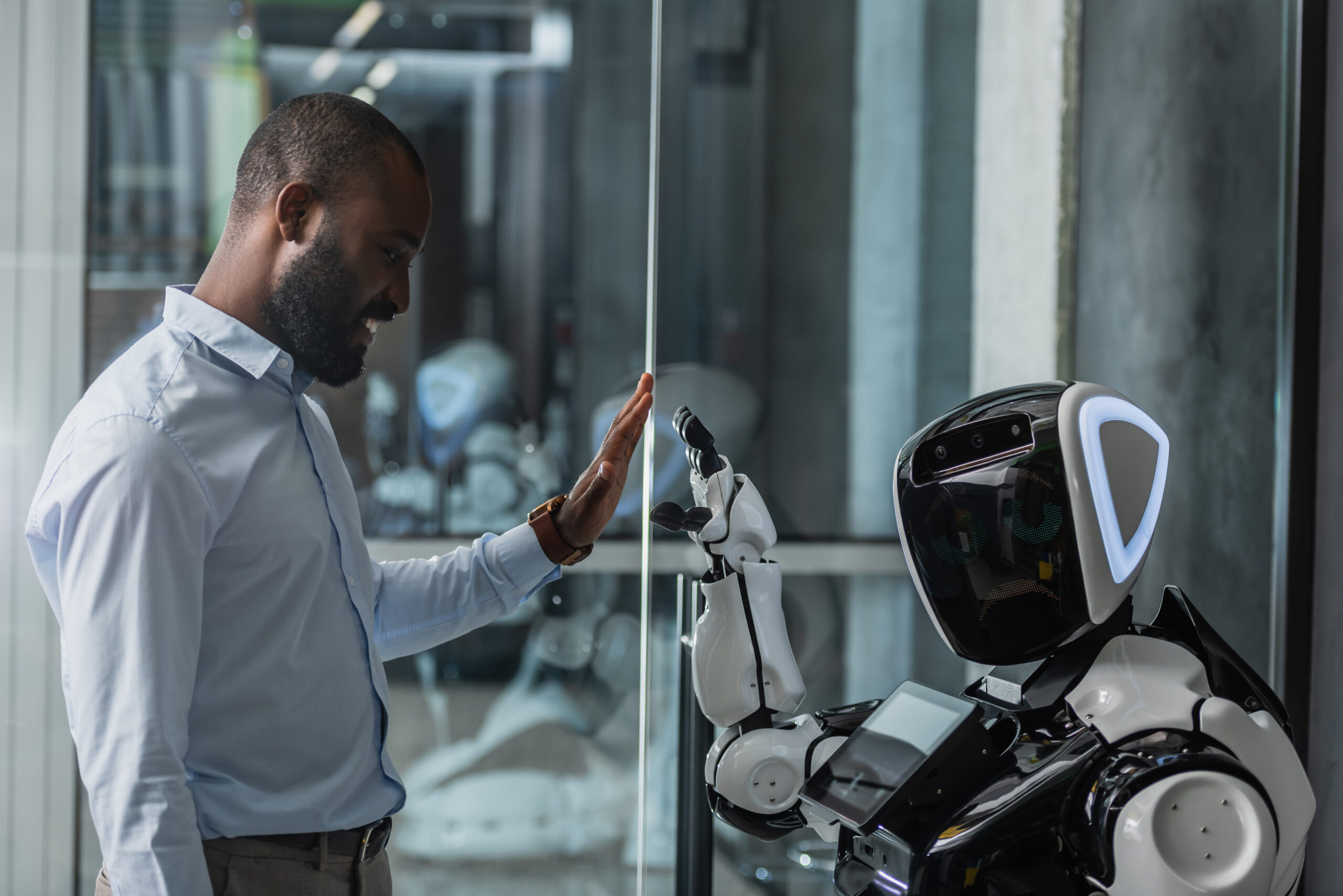 happy man giving high five to a humanoid robot at workplace
