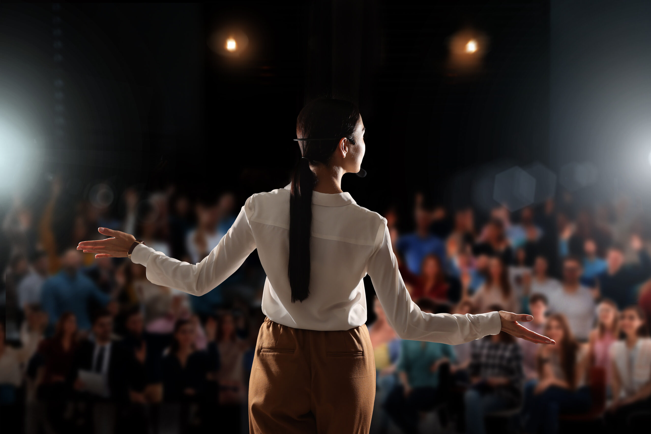 female motivational speaker with headset performing on stage