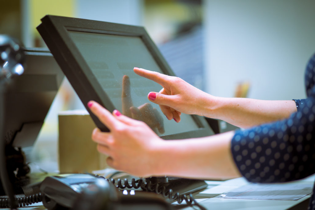 Saleswoman doing process payment on touchscreen POS.