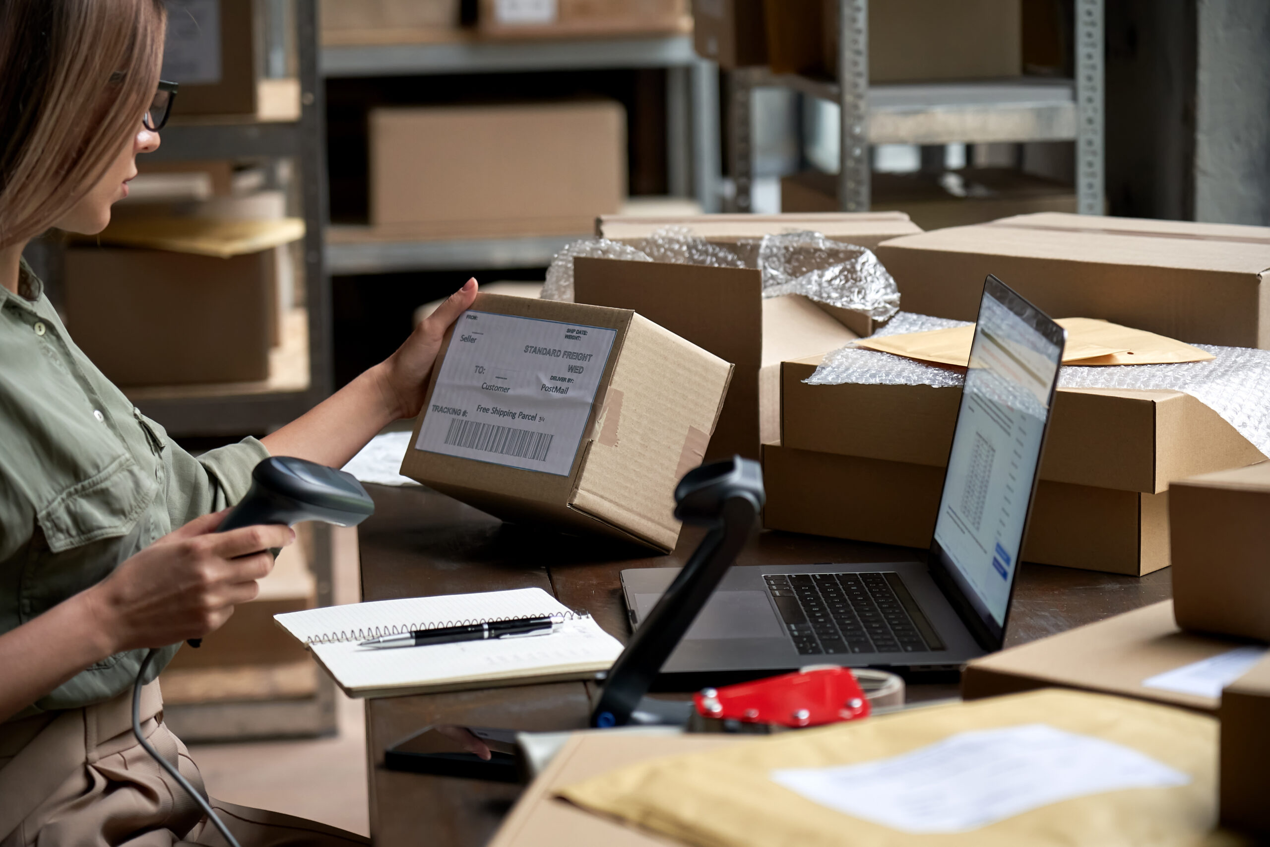 female warehouse worker scans packages at desk