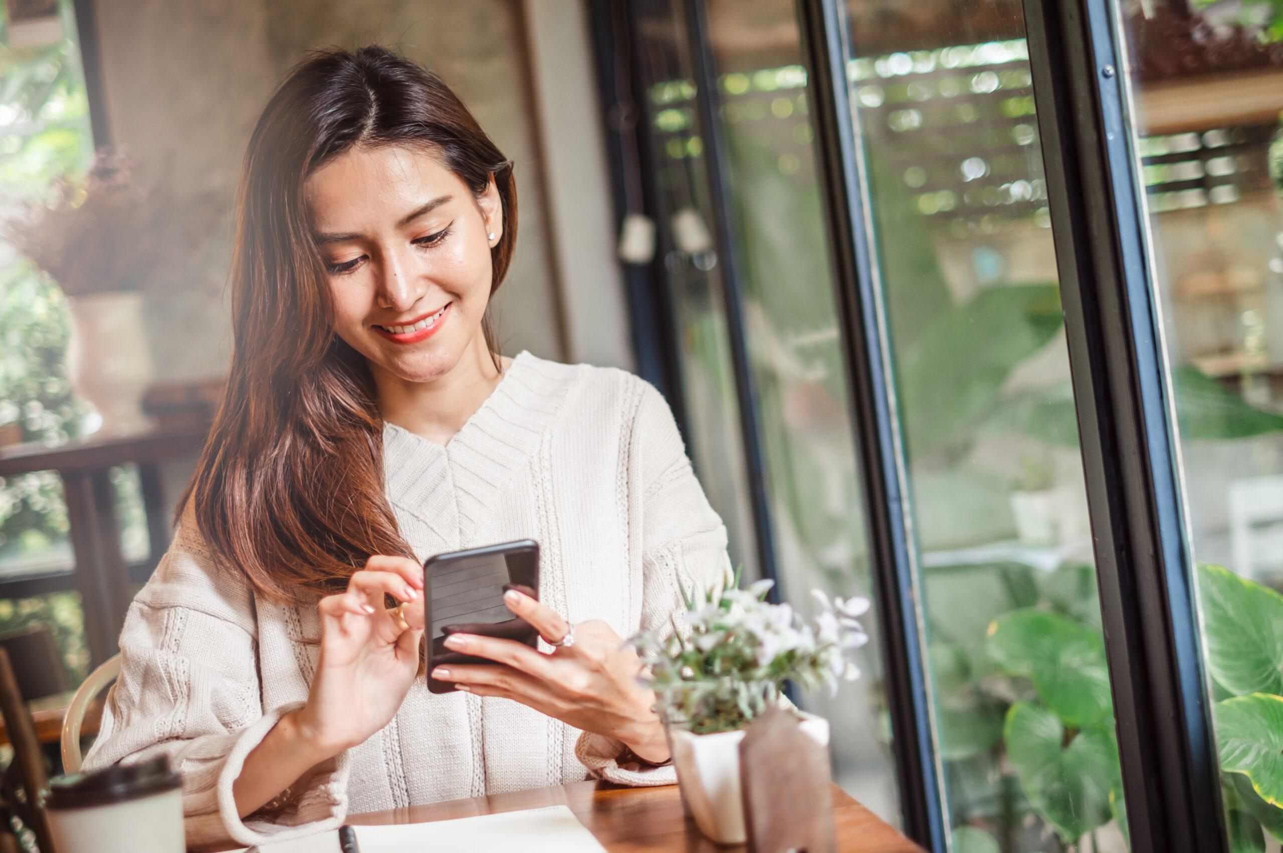 Young Asian beautiful woman using smart phone for business, transfer money, financial, internet banking. in coffee shop cafe