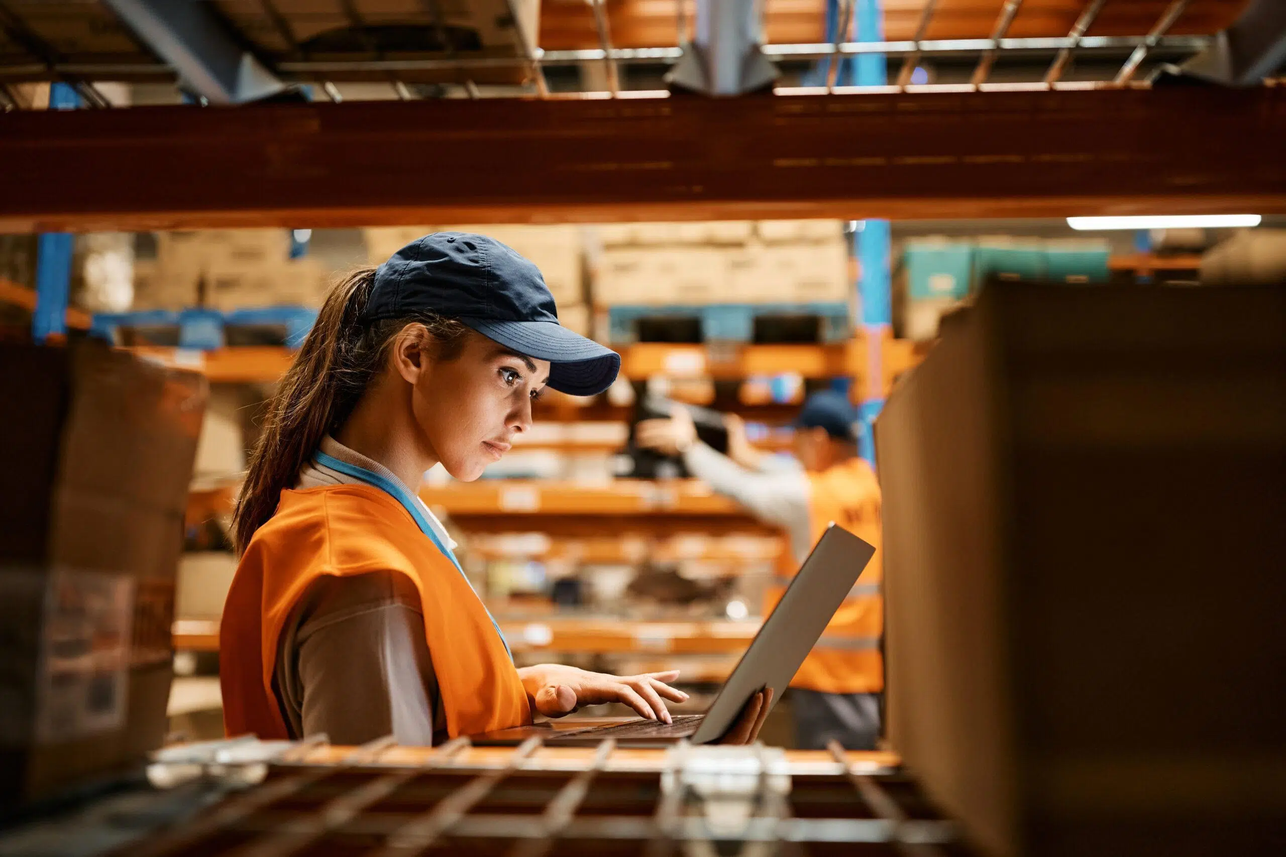 Female staff working on laptop at warehouse