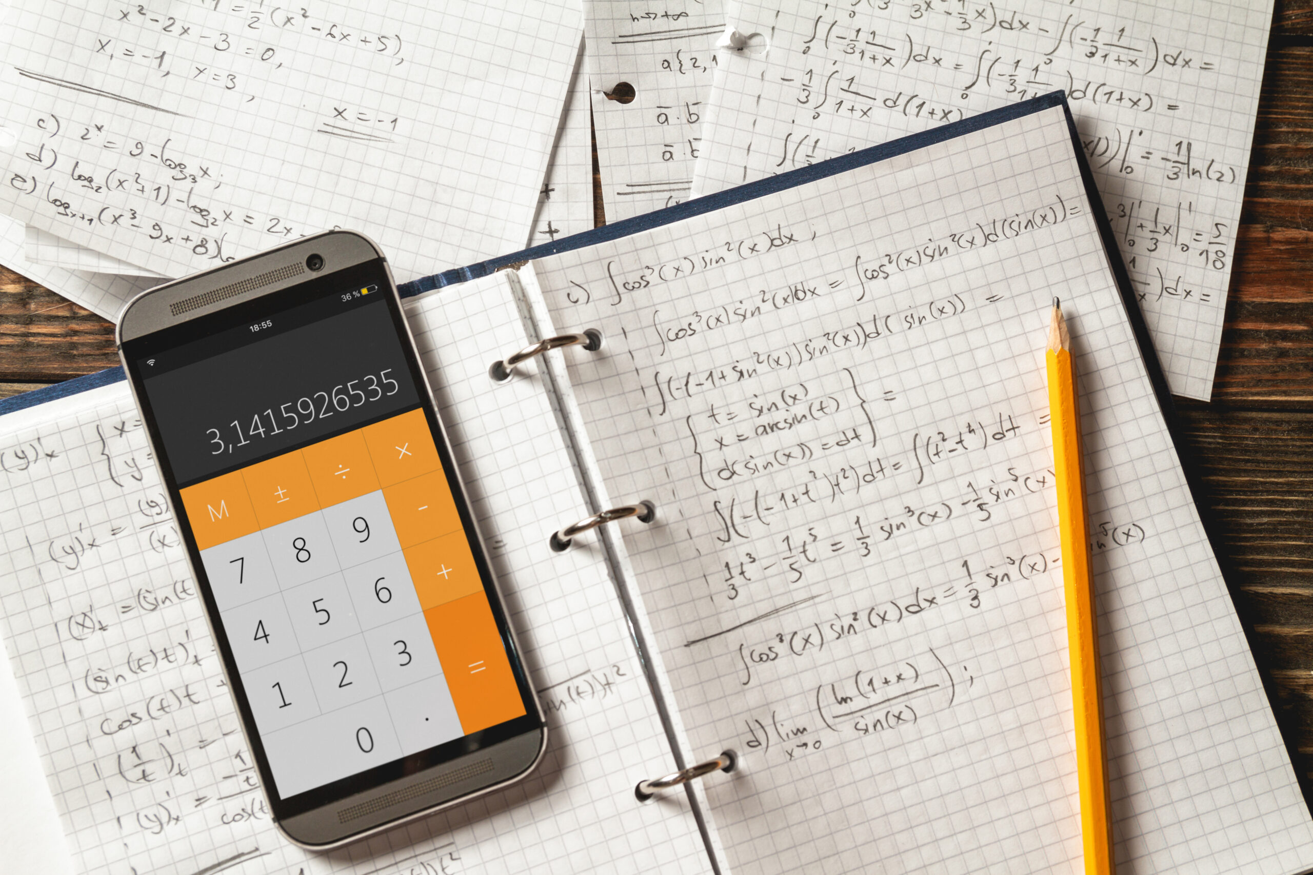 mathematical equations written in a notebook with a calculator next to it