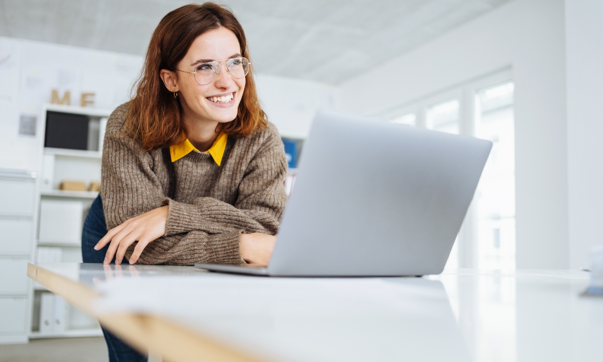 young modern businesswoman leans on the desk and looks to the side laughing