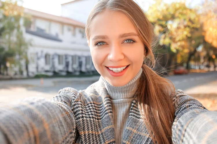 Beautiful young woman taking selfie outdoors