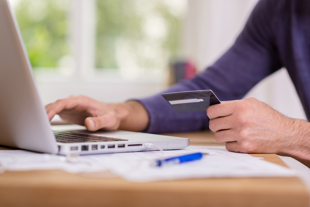 man holding a credit card while using laptop