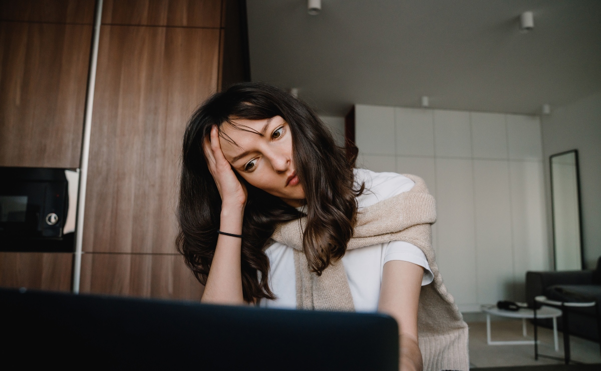 Young serious woman sitting with laptop reading a review about whether onlyshares is legit.