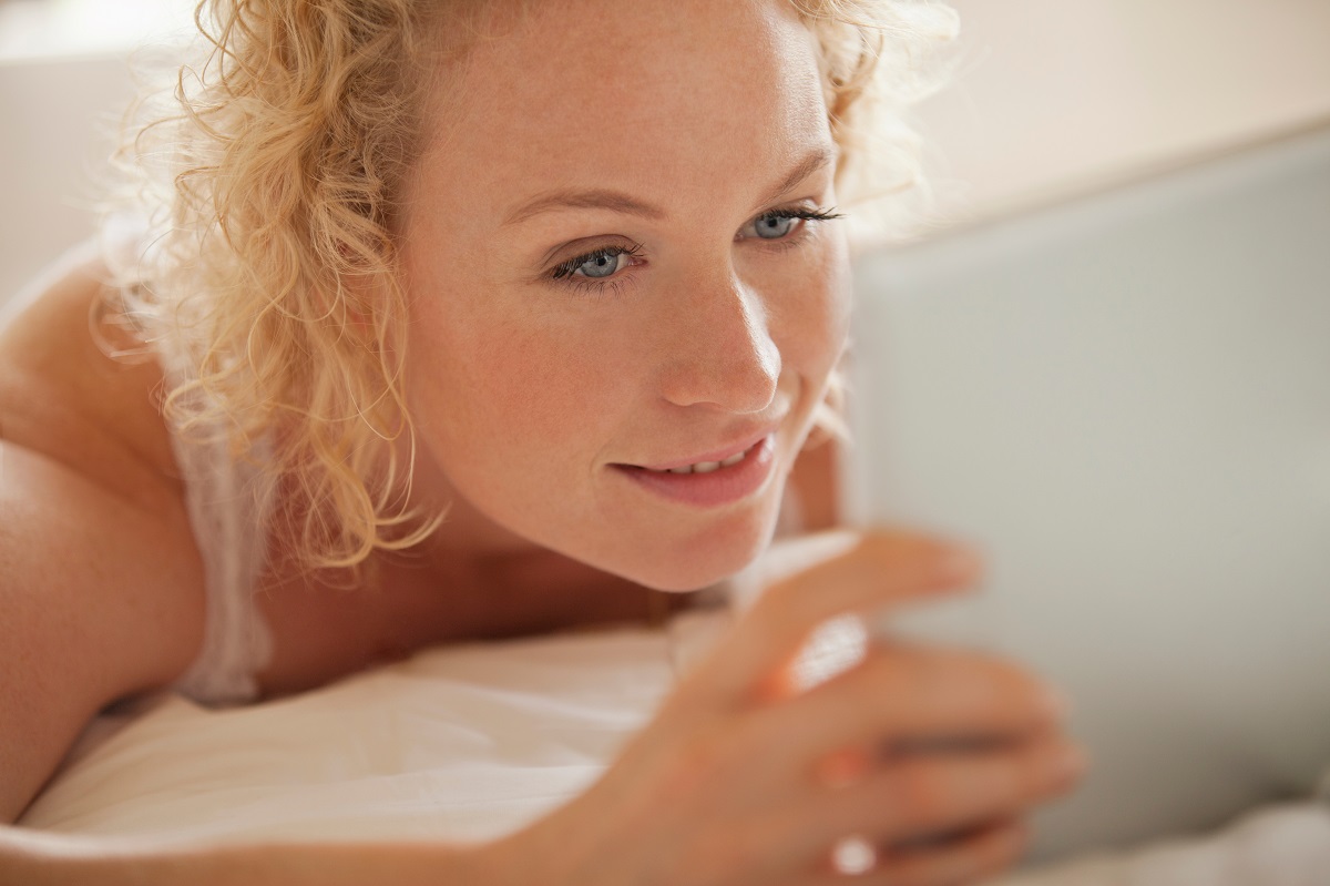 attractive blonde using a digital tablet in bed